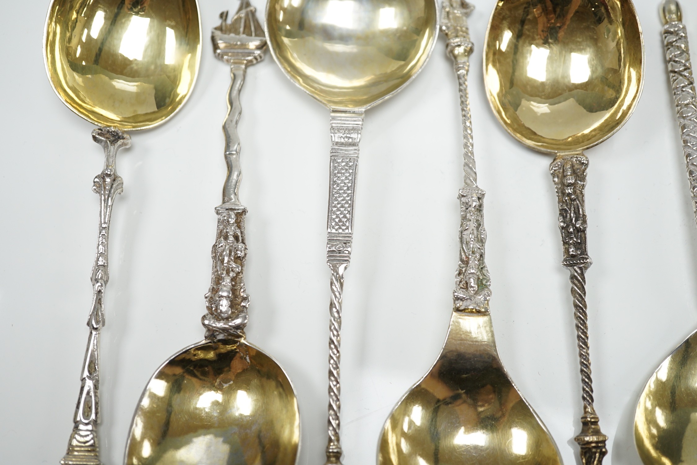 Twelve assorted 19th century and later Scandinavian or Dutch? gilt or parcel gilt white metal spoons, with differing stems including apostle, largest 18.8cm, 19.3oz.